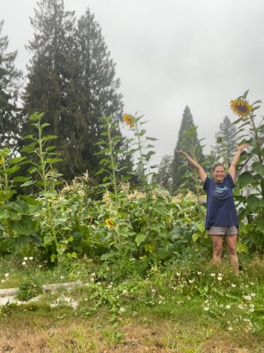 Person standing among tall sunflowers in a garden